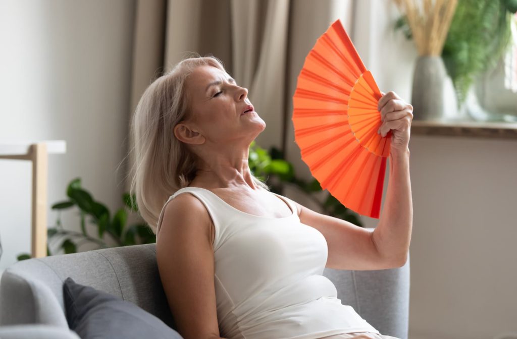 A woman using a fan because her air conditioner isn't working.